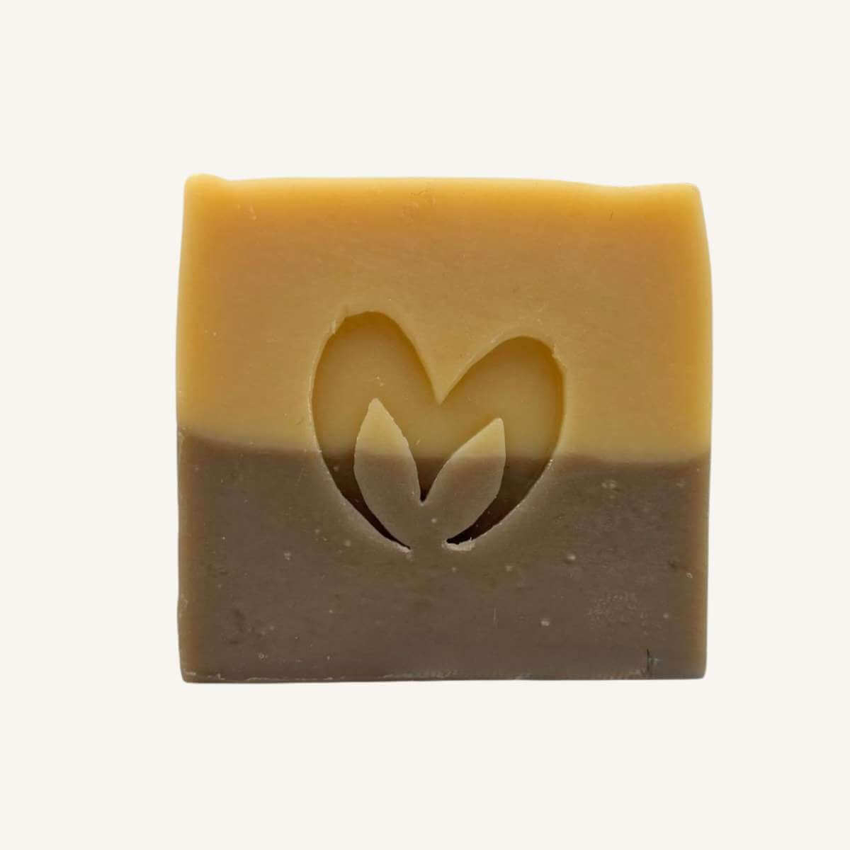 Primer plano del jabón de avena y miel en dos colores con el logo de Misey grabado en el centro.